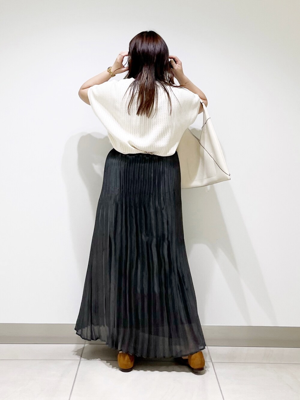 ブラック系のスカート、ホワイト系のニット/セーター、ホワイト系のトートバッグを着用したレディースの夏コーディネートの4枚目の写真