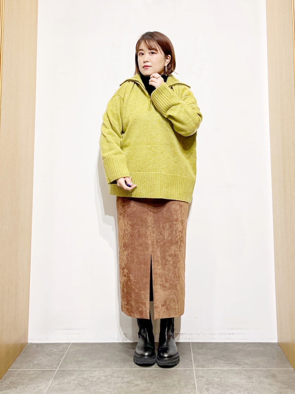 グリーン系のニット/セーター、ブラック系のニット/セーター、ブラウン系のスカートを着用したレディースの冬コーディネートの2枚目の写真