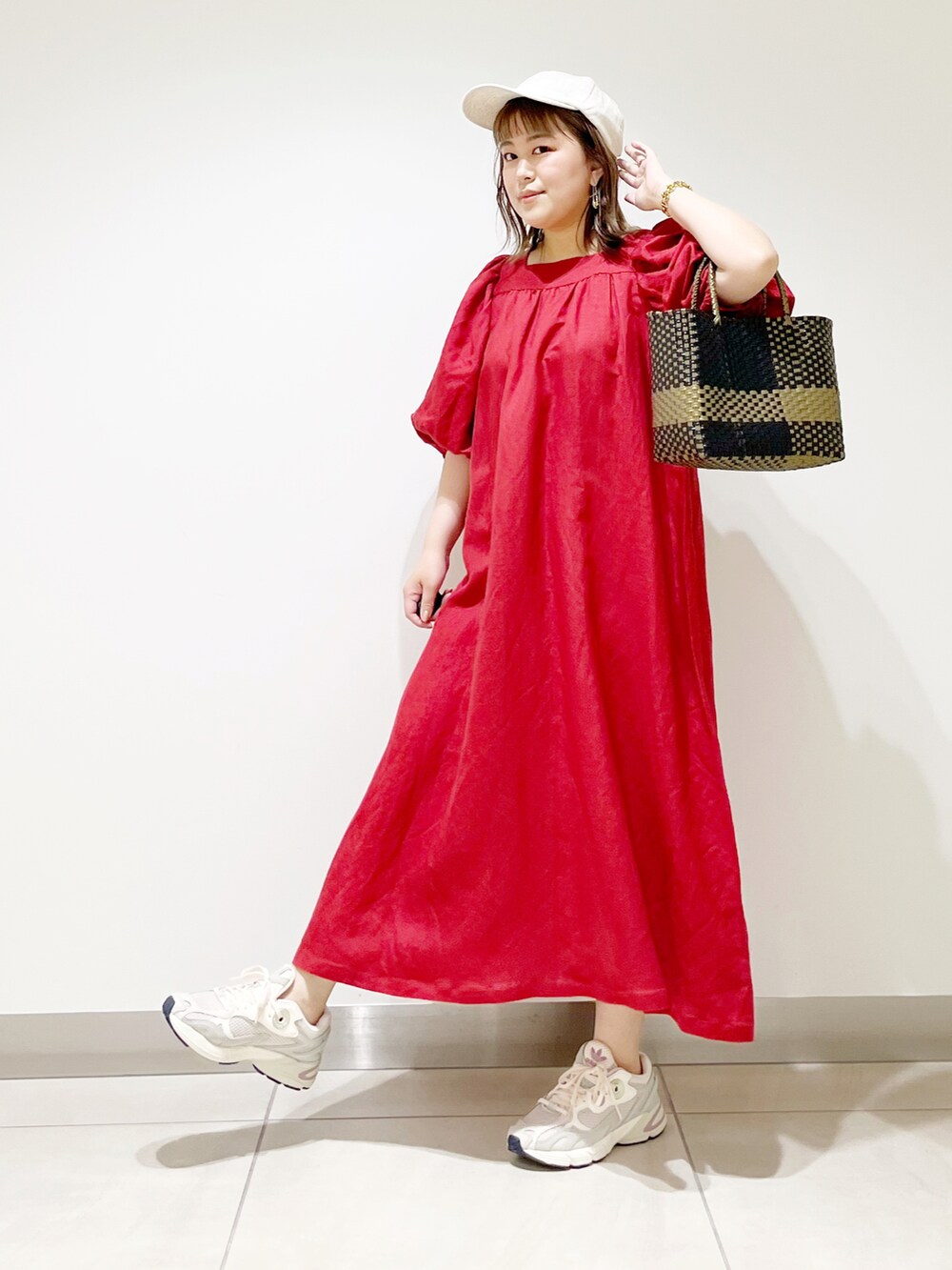 レッド系のワンピース、ホワイト系のスニーカー、ブラック系のトートバッグを着用したレディースの夏コーディネートの2枚目の写真