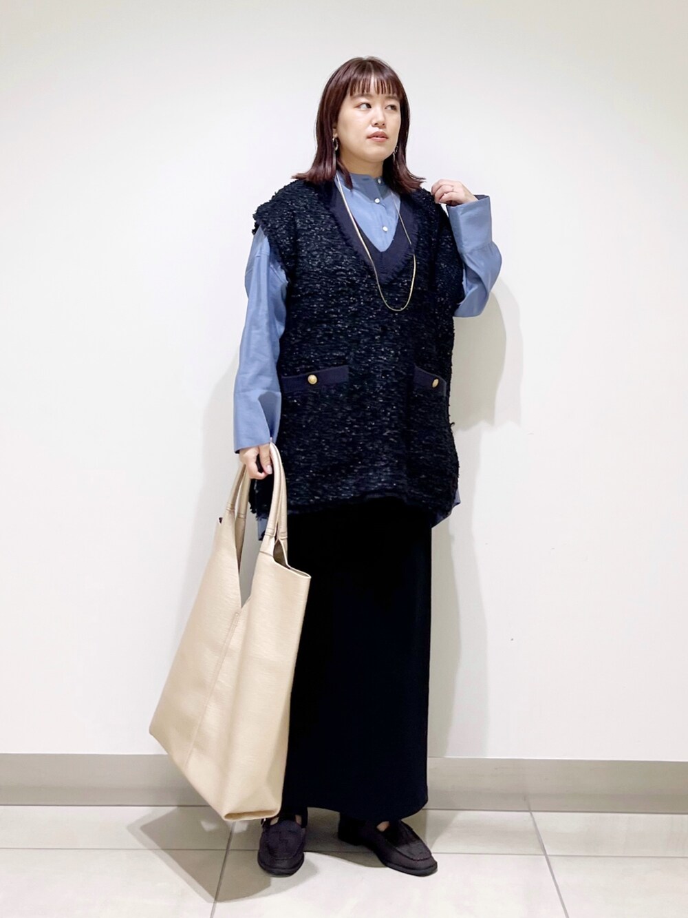 ブルー系のシャツ/ブラウス、ブラック系のスカート、ゴールド系のトートバッグを着用したレディースの秋コーディネートの8枚目の写真