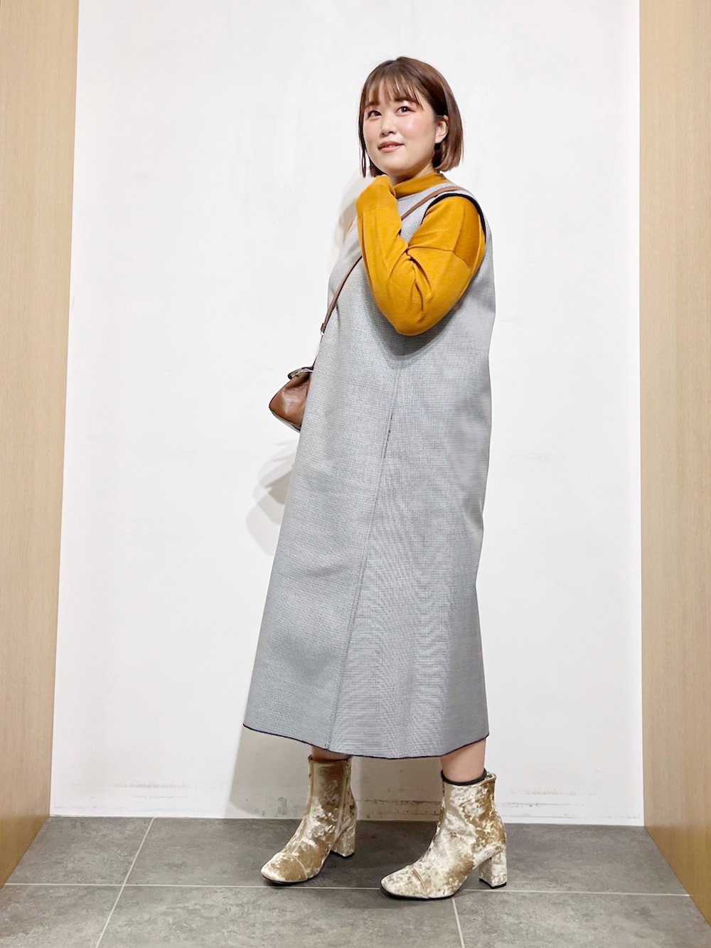 ブラック系のワンピース、ベージュ系のブーツ、ブラウン系のショルダーバッグを着用したレディースの秋コーディネートの5枚目の写真