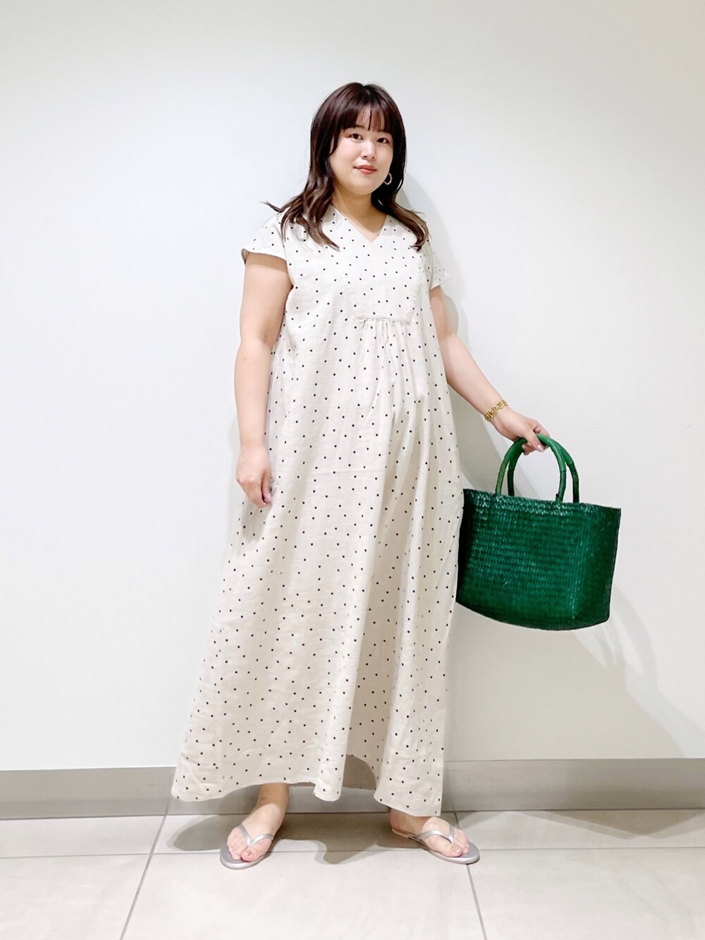 ベージュ系のワンピース、グリーン系のハンドバッグ、シルバー系のサンダルを着用したレディースの春コーディネートの9枚目の写真