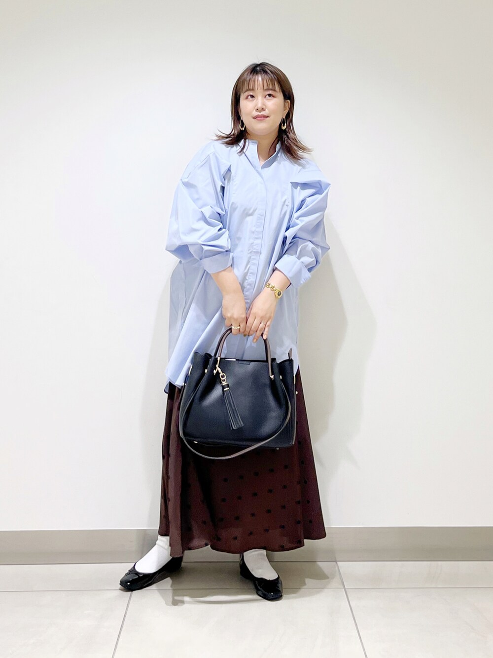 パープル系のワンピース、ブラック系のトートバッグ、ブラウン系のスカートを着用したレディースの秋コーディネートの2枚目の写真