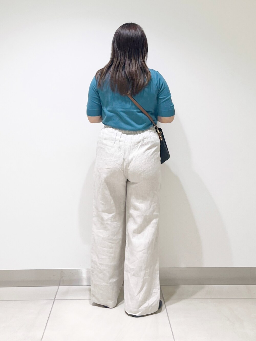 ブルー系のニット/セーター、ベージュ系のその他パンツ、ブラック系のショルダーバッグを着用したレディースの春コーディネートの4枚目の写真