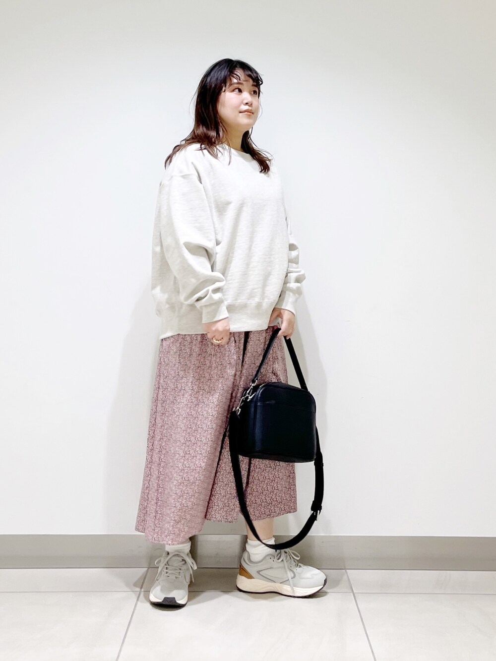 グレー系のスウェット、ピンク系のスカート、ブラック系のショルダーバッグを着用したレディースの春コーディネートの2枚目の写真