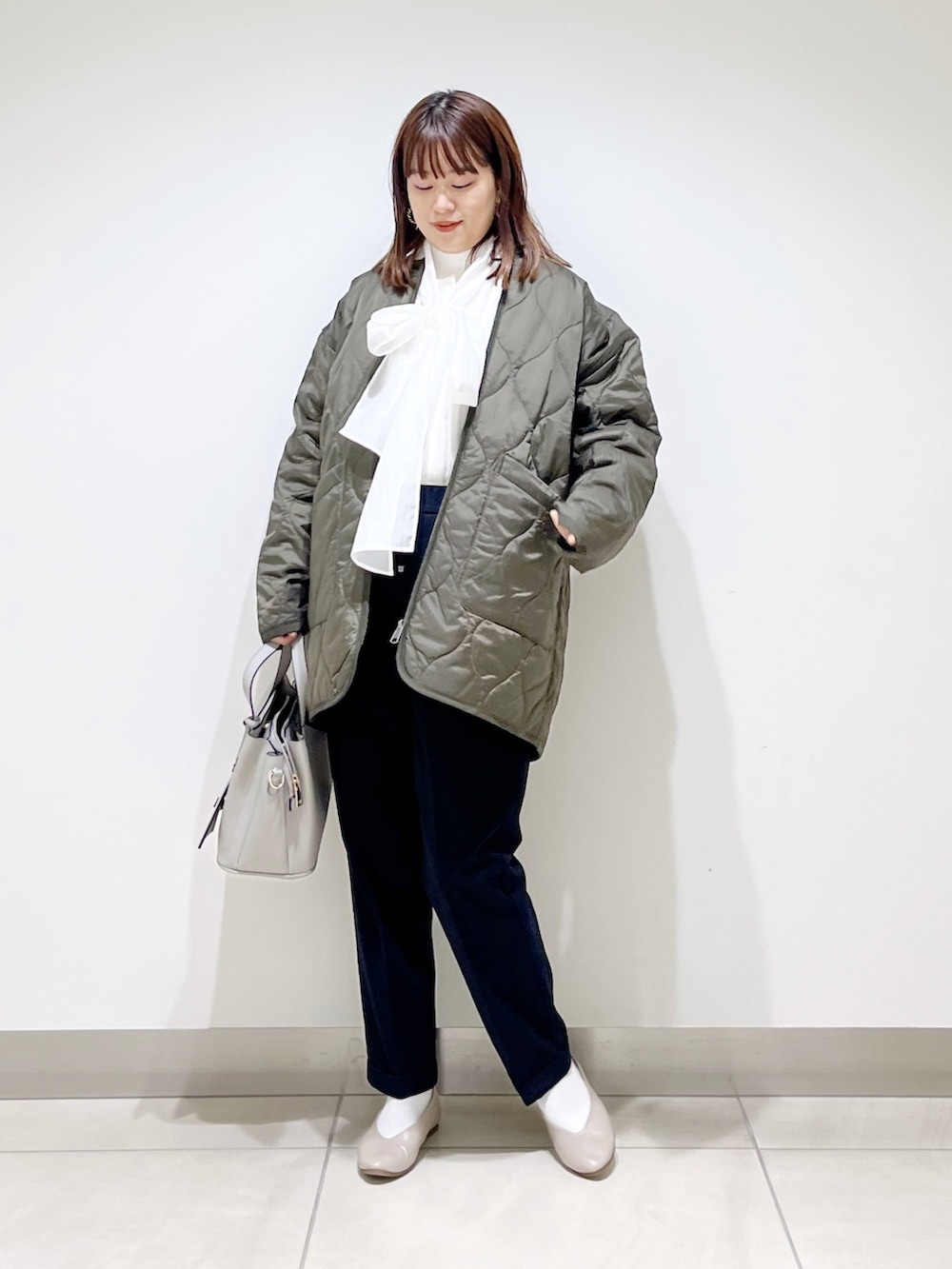 グリーン系のダウンジャケット/コート、ブルー系のパンツ、グレー系のトートバッグを着用したレディースの秋コーディネートの3枚目の写真