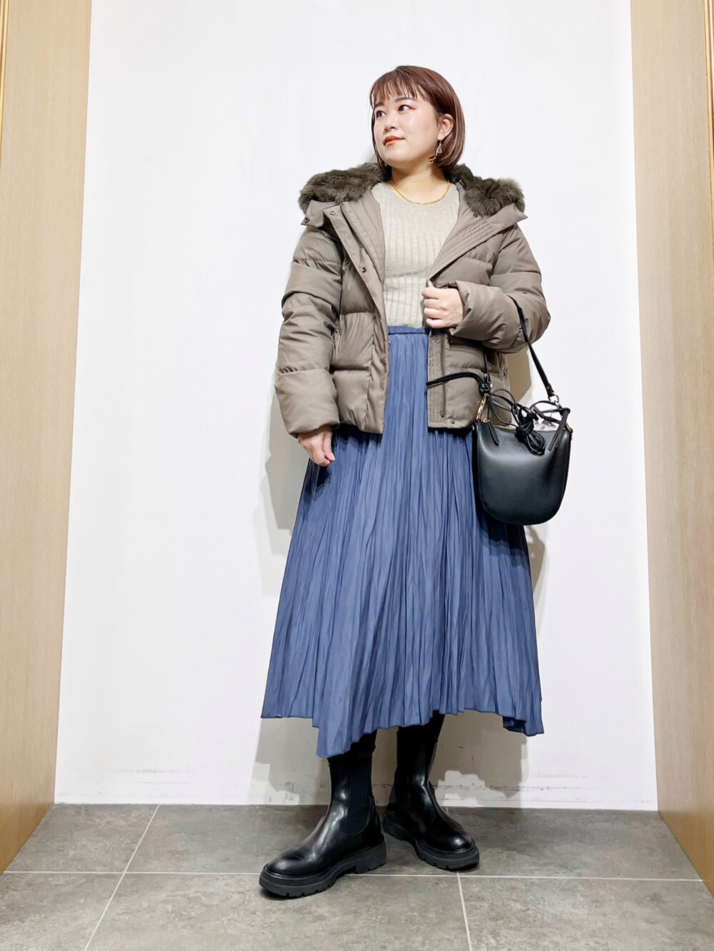 グリーン系のダウンジャケット/コート、ベージュ系のニット/セーター、ブラック系のショルダーバッグを着用したレディースの冬コーディネートの4枚目の写真