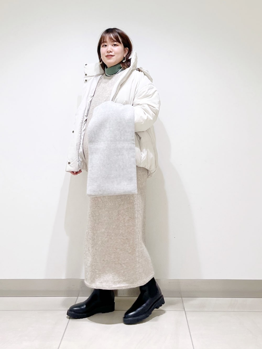 ホワイト系のダウンジャケット/コート、ベージュ系のワンピース、グリーン系のニット/セーターを着用したレディースの冬コーディネートの10枚目の写真