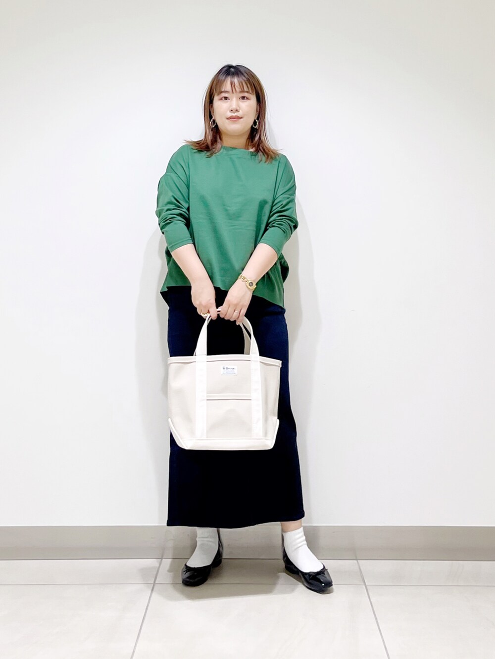 グリーン系のTシャツ/カットソー、ブルー系のスカート、ホワイト系のトートバッグを着用したレディースの秋コーディネートの3枚目の写真