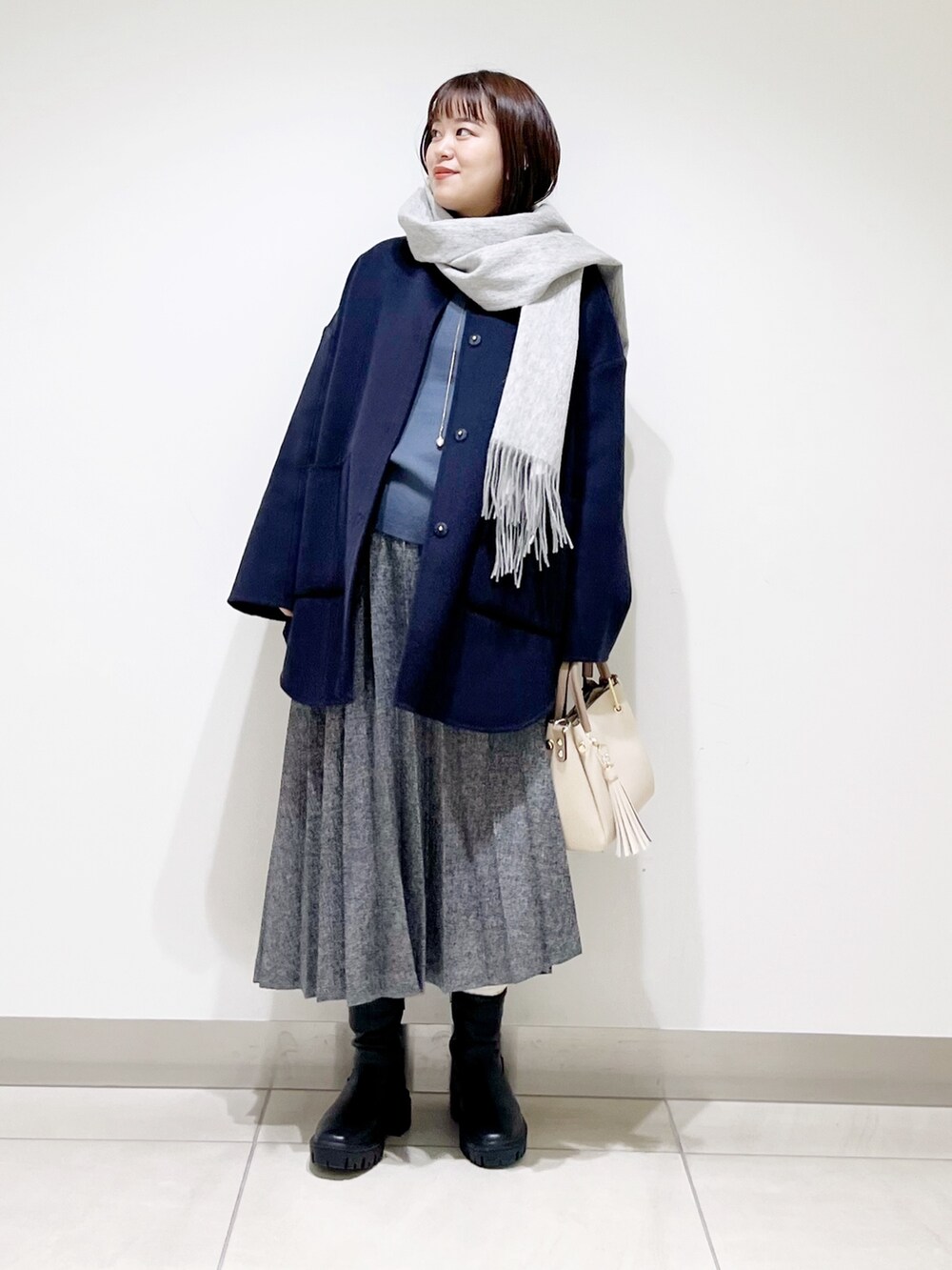 ブルー系のノーカラージャケット、グレー系のニット/セーター、ブルー系のスカートを着用したレディースの秋コーディネートの2枚目の写真
