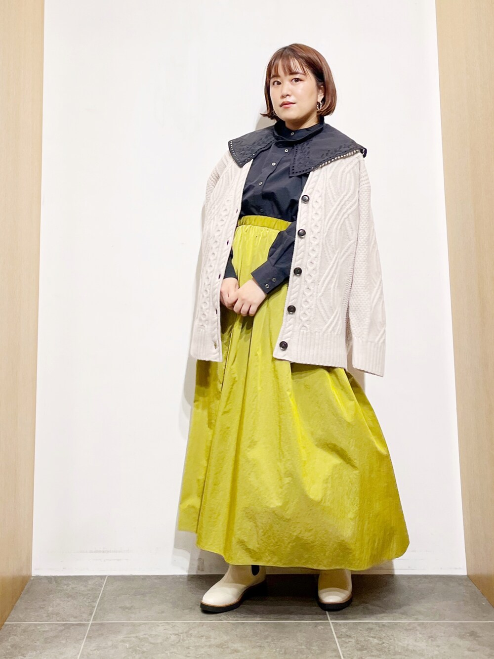 ブラック系のシャツ/ブラウス、ベージュ系のカーディガン/ボレロ、イエロー系のスカートを着用したレディースの秋コーディネートの3枚目の写真