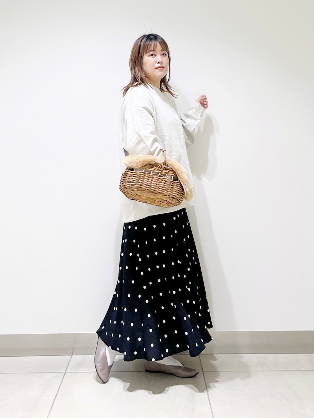 グレー系のスウェット、ベージュ系のかごバッグ、ブラック系のスカートを着用したレディースの秋コーディネートの3枚目の写真