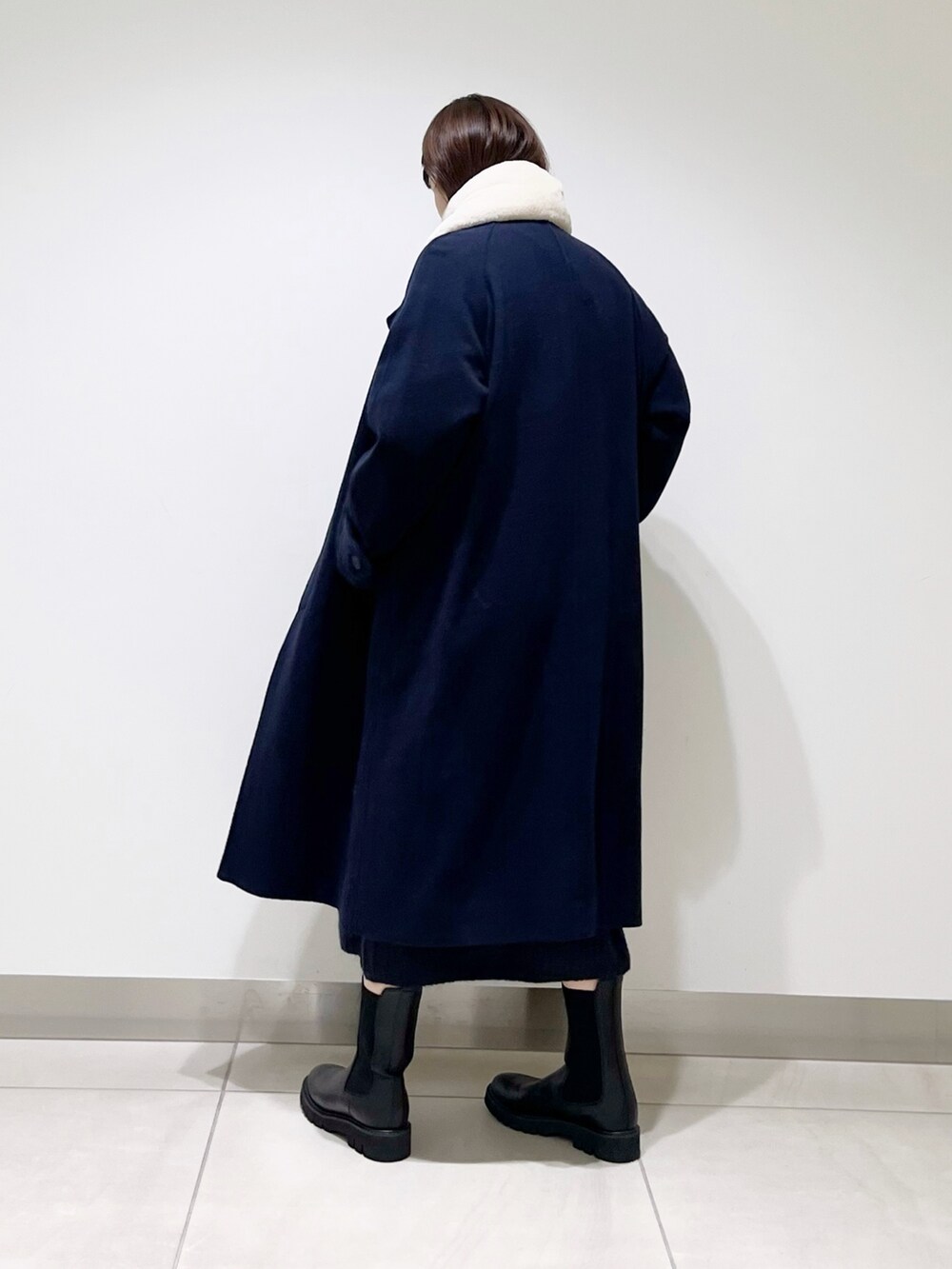 ブルー系のステンカラーコート、ブルー系のワンピース、ブラック系のブーツを着用したレディースの冬コーディネートの3枚目の写真