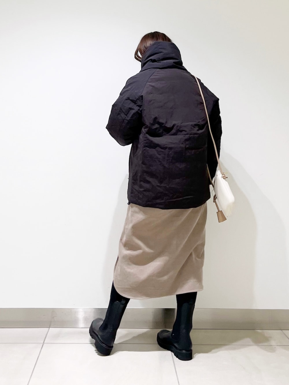 ベージュ系のワンピース、ブラック系のダウンジャケット/コート、ブラック系のブーツを着用したレディースの冬コーディネートの6枚目の写真