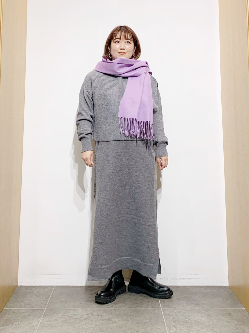 グレー系のワンピース、ブラック系のブーツ、パープル系のマフラーを着用したレディースの冬コーディネートの5枚目の写真