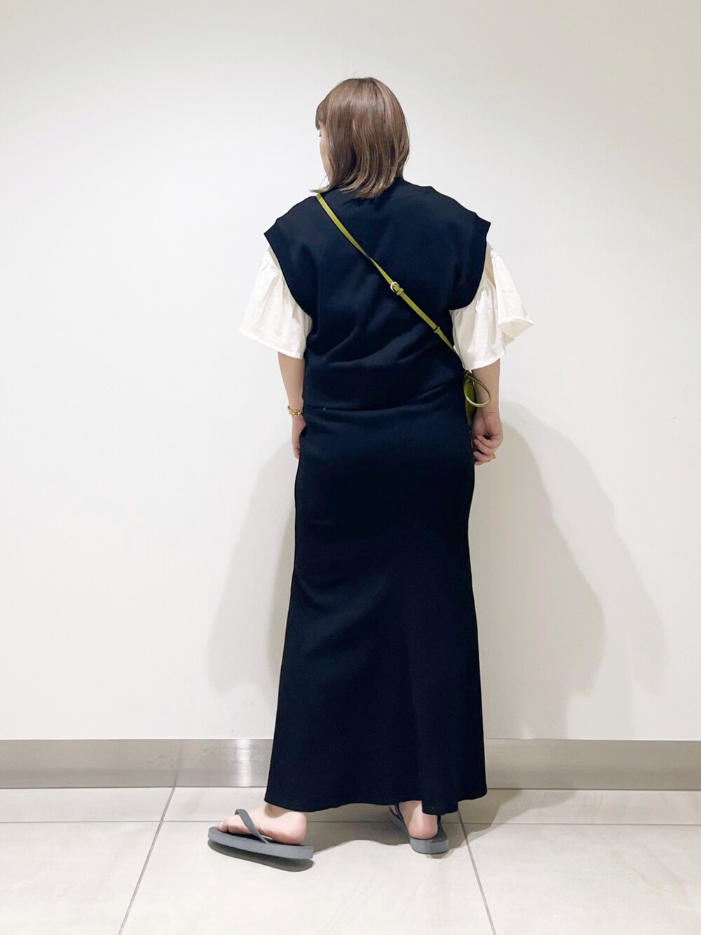 ブラック系のベスト、ブラック系のスカート、グリーン系のショルダーバッグを着用したレディースの春コーディネートの4枚目の写真