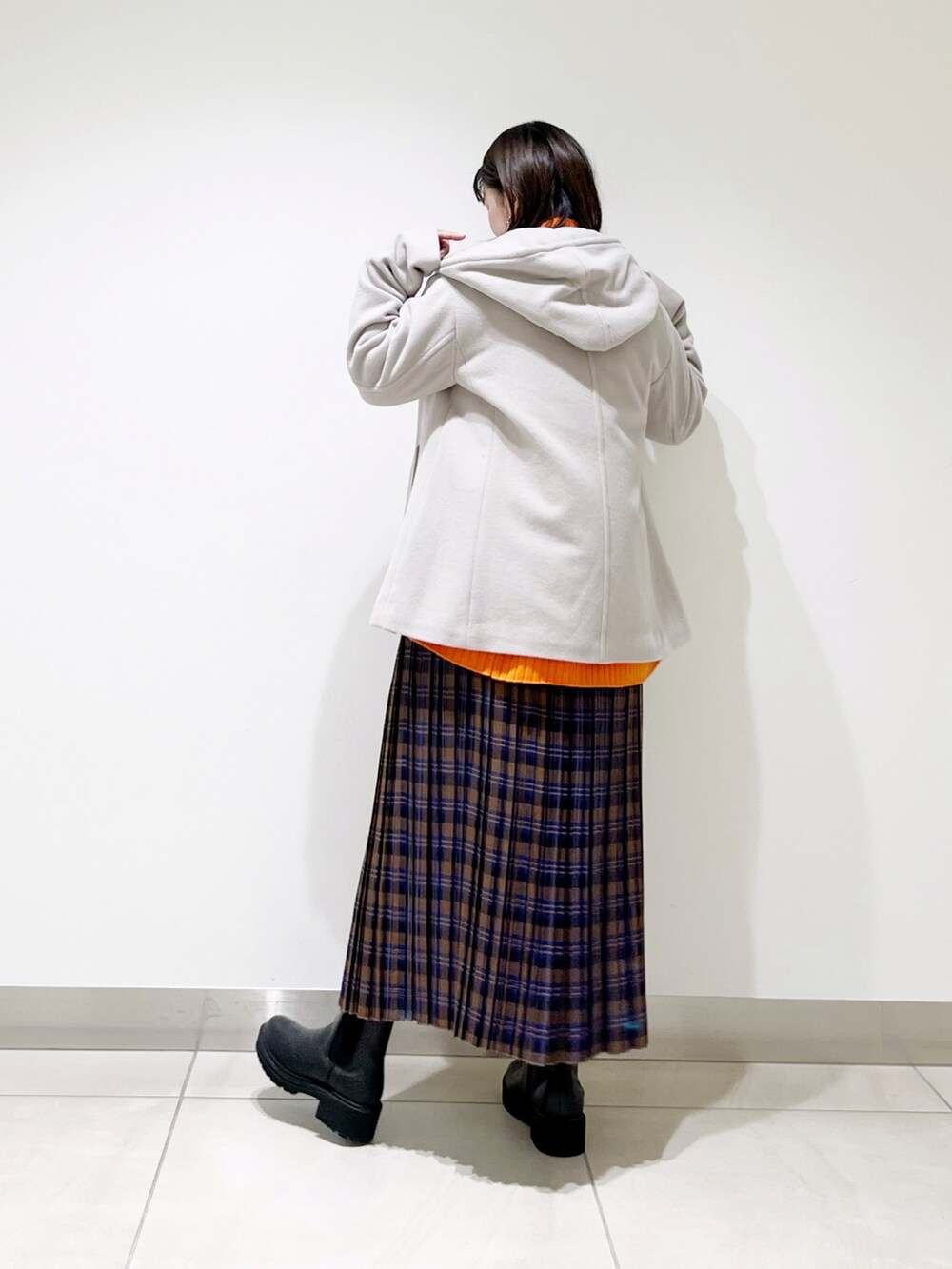 ベージュ系のその他アウター、オレンジ系のニット/セーター、ブルー系のスカートを着用したレディースの秋コーディネートの4枚目の写真