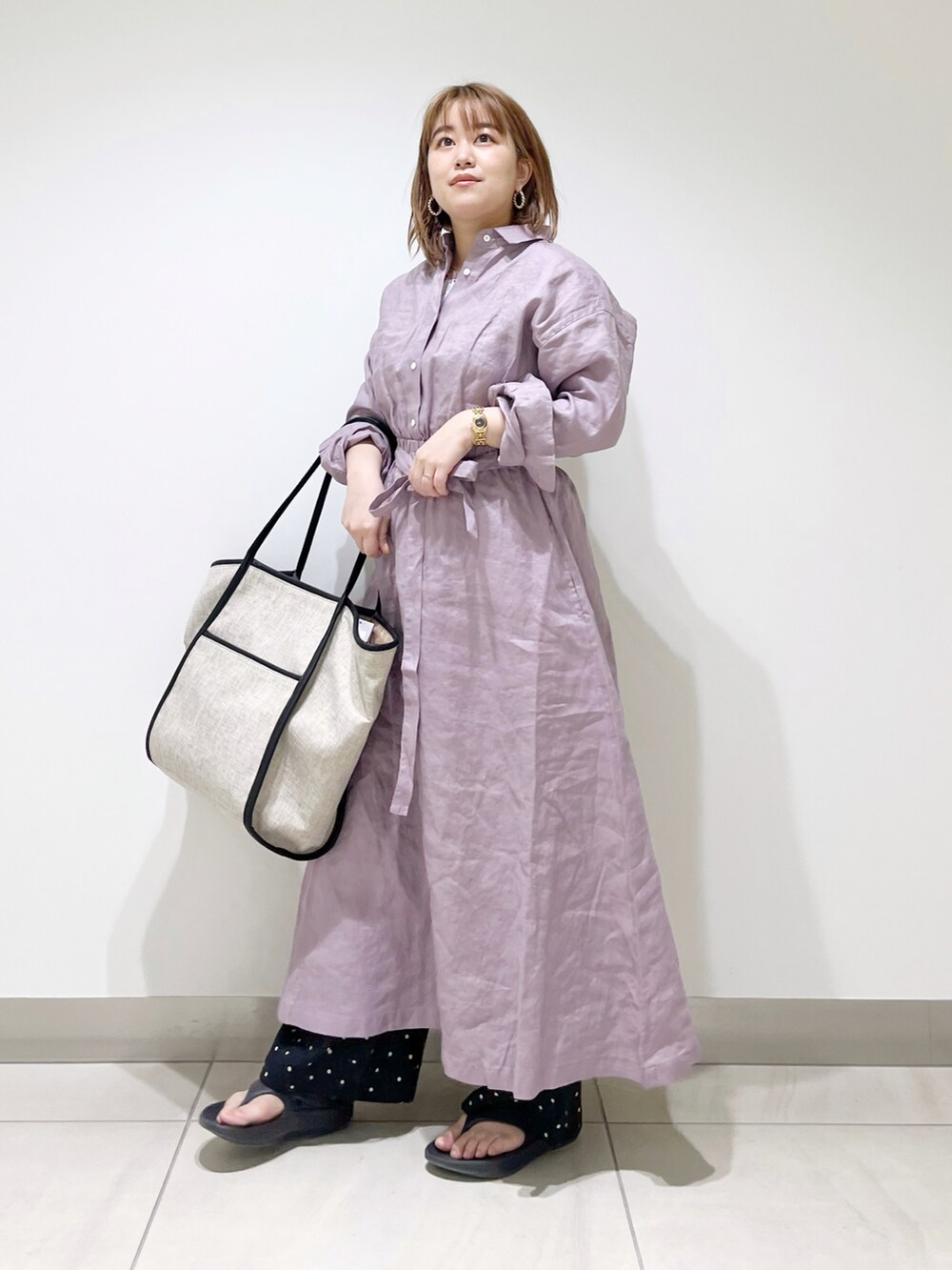 パープル系のワンピース、ブラック系のトートバッグ、ブラック系のサンダルを着用したレディースの春コーディネートの5枚目の写真