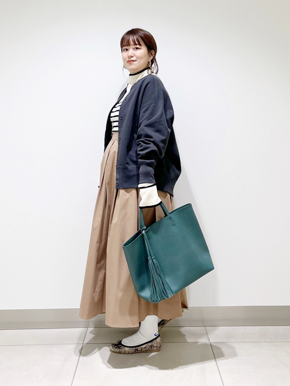 グリーン系のトートバッグ、ベージュ系のスカート、その他のバレエシューズを着用したレディースの秋コーディネートの3枚目の写真