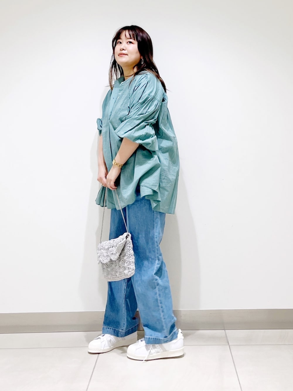 グリーン系のシャツ/ブラウス、ブルー系のデニムパンツ、シルバー系のバッグを着用したレディースの春コーディネートの2枚目の写真