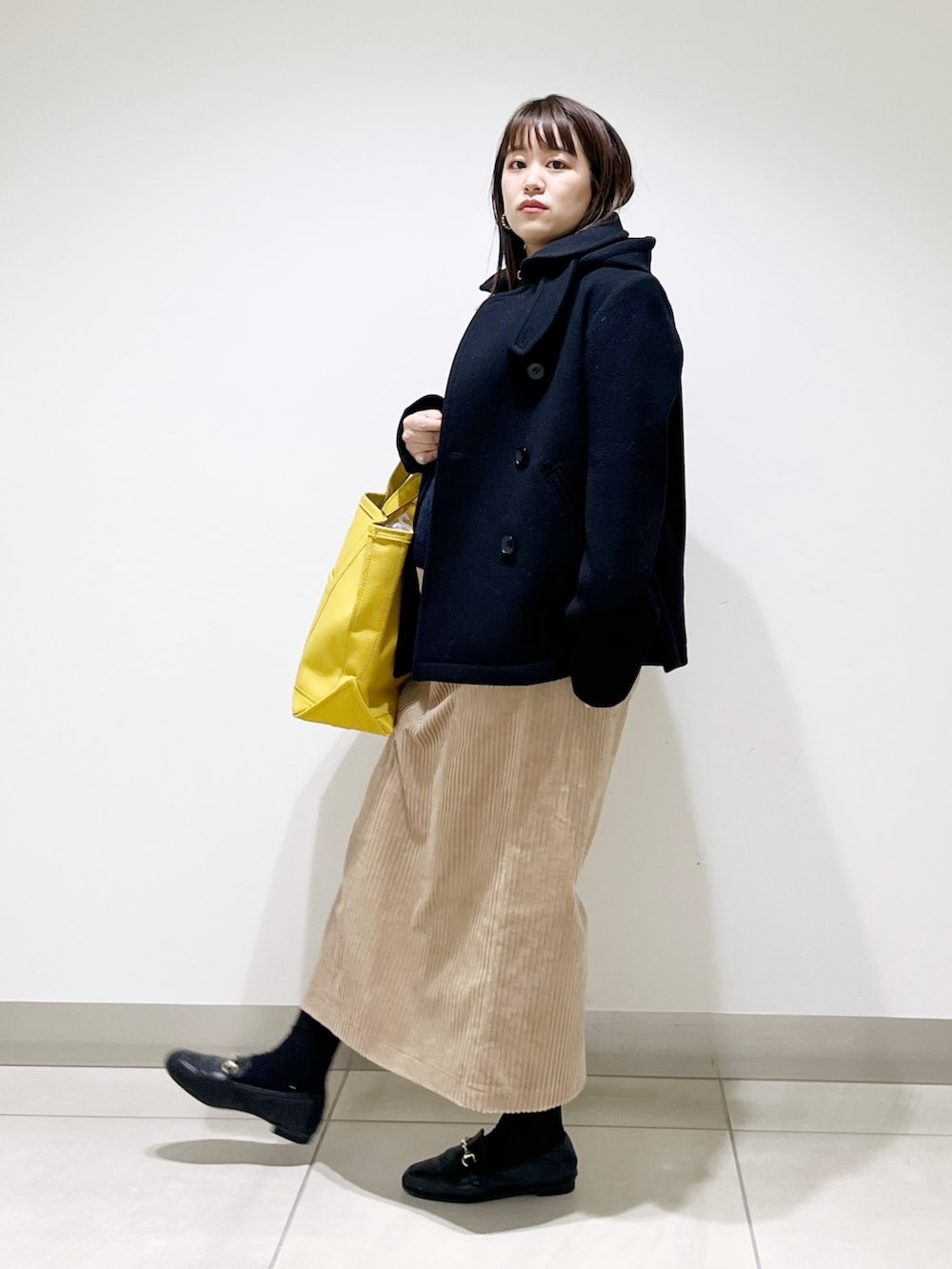 ブラック系のピーコート、ブルー系のニット/セーター、ブラック系のローファーを着用したレディースの冬コーディネートの2枚目の写真