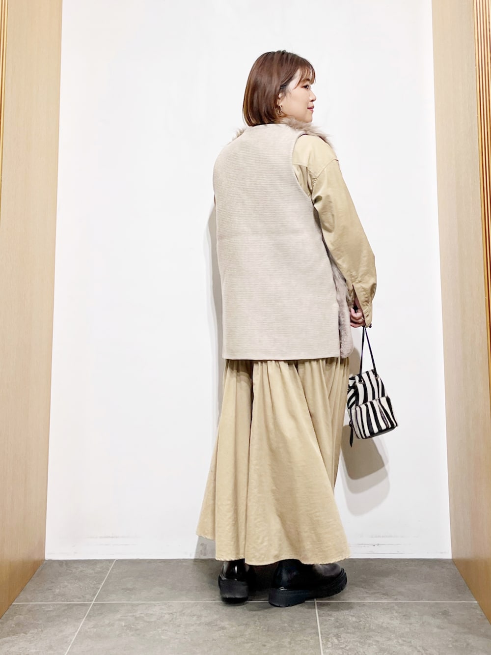 ベージュ系のベスト、ベージュ系のワンピース、その他のバッグを着用したレディースの秋コーディネートの4枚目の写真