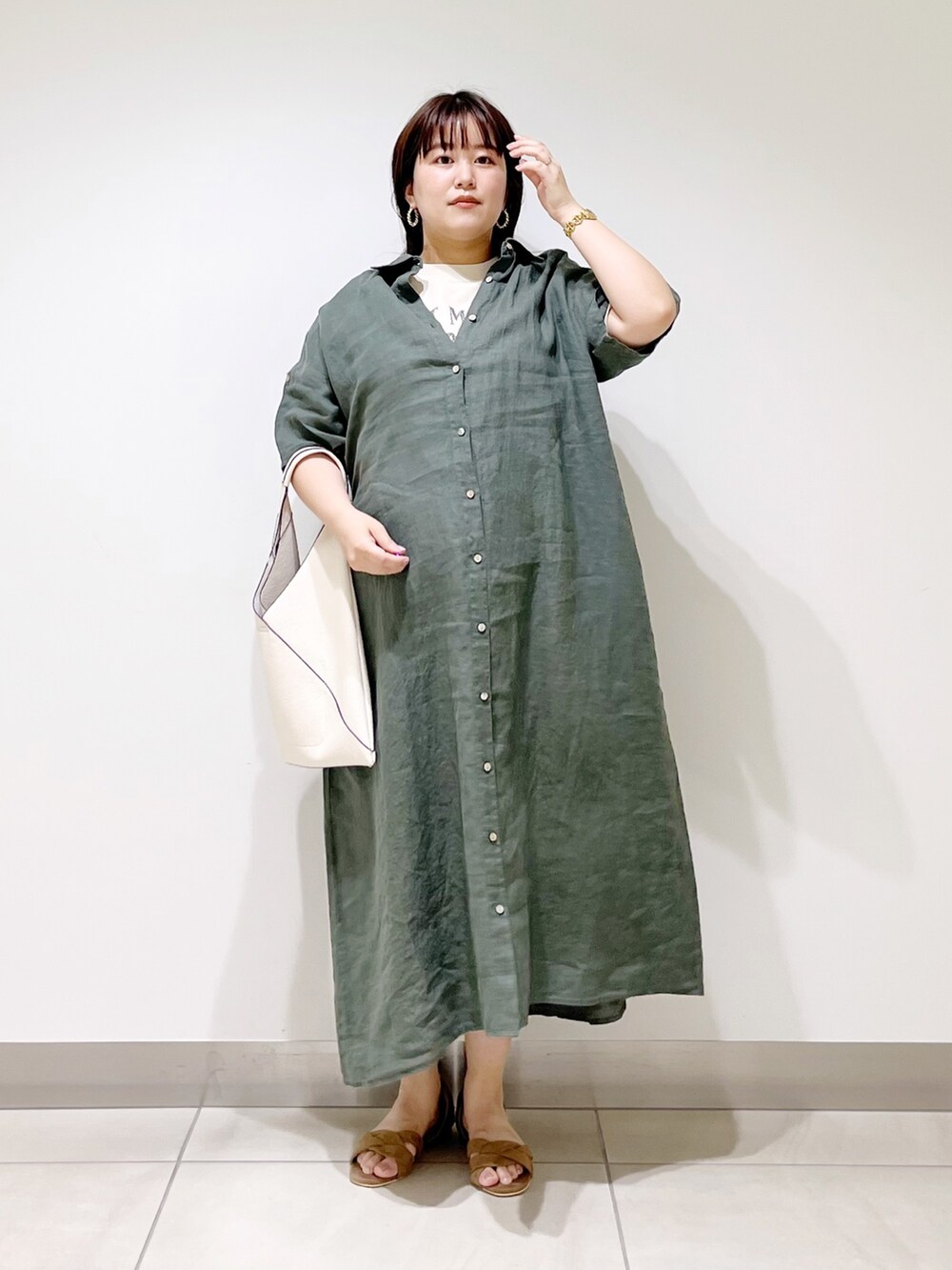 グリーン系のワンピース、ホワイト系のトートバッグ、ベージュ系のサンダルを着用したレディースの春コーディネートの2枚目の写真