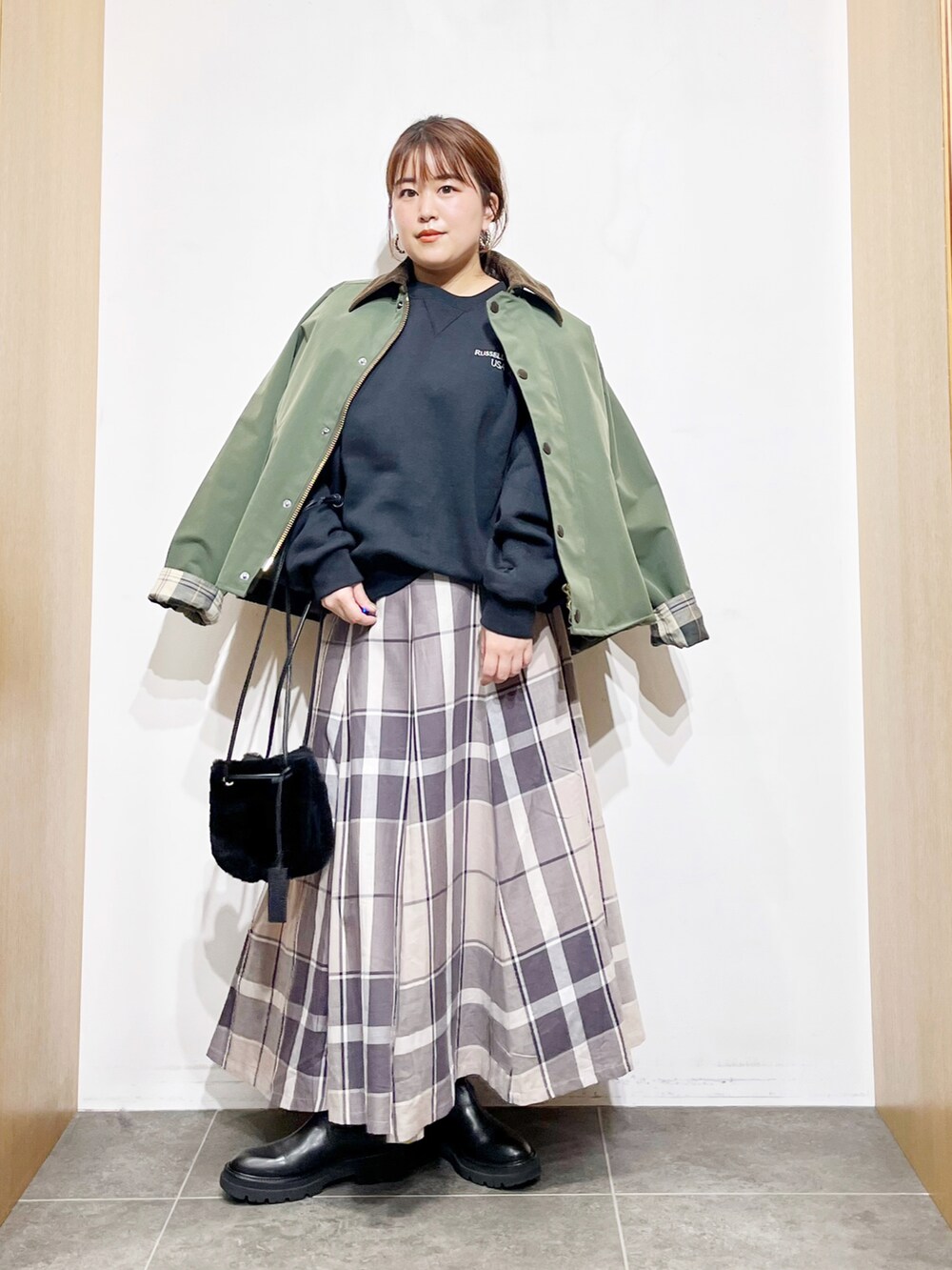 グリーン系のその他アウター、ブラック系のスウェット、ブラック系のハンドバッグを着用したレディースの冬コーディネートの3枚目の写真