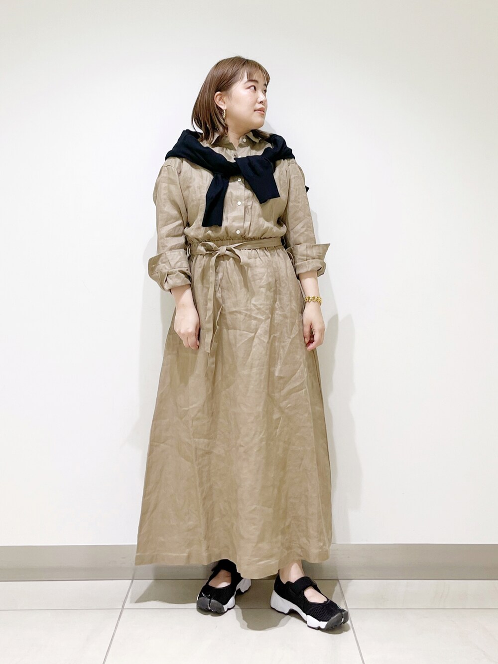 ベージュ系のワンピース、ブラック系のカーディガン/ボレロ、ブラック系のスニーカーを着用したレディースの春コーディネートの5枚目の写真