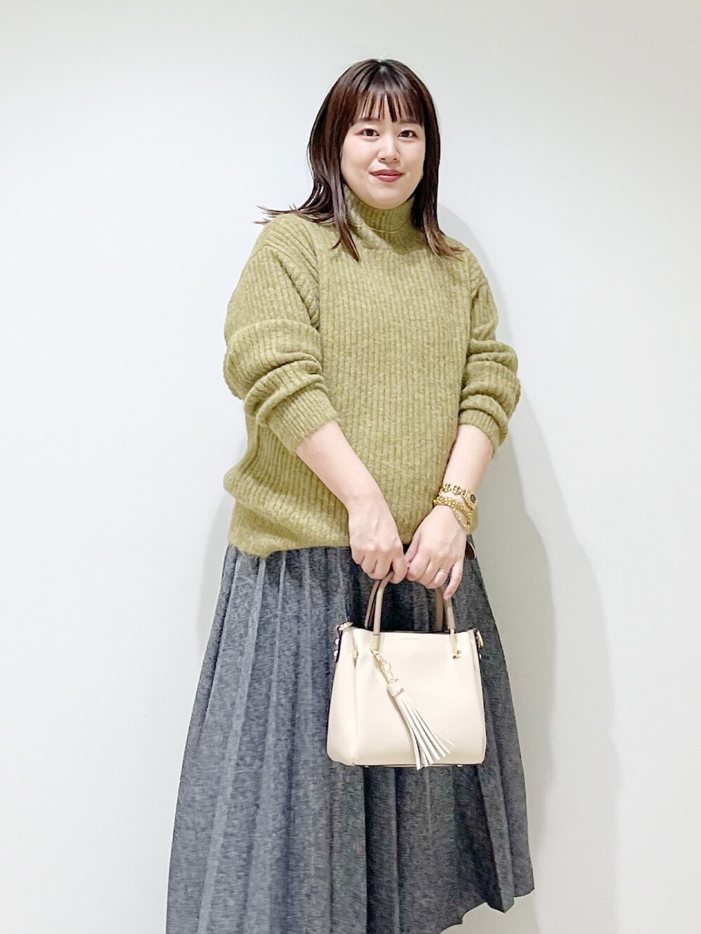 グリーン系のニット/セーター、ブルー系のスカート、ホワイト系のトートバッグを着用したレディースの冬コーディネートの4枚目の写真