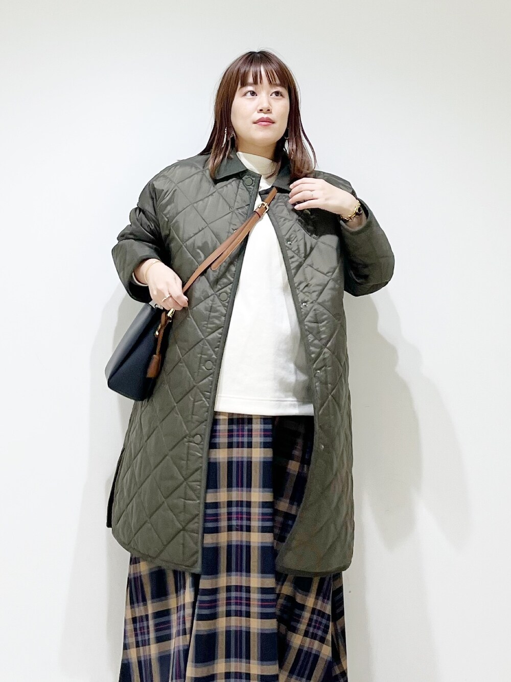 グリーン系のダウンジャケット/コート、ホワイト系のトップス、ブラウン系のスカートを着用したレディースの秋コーディネートの5枚目の写真
