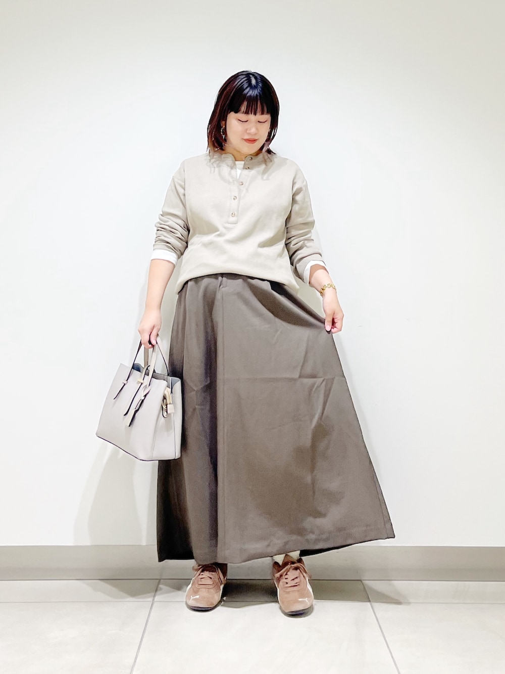ベージュ系のTシャツ/カットソー、ブラウン系のスカート、グレー系のトートバッグを着用したレディースの秋コーディネートの3枚目の写真