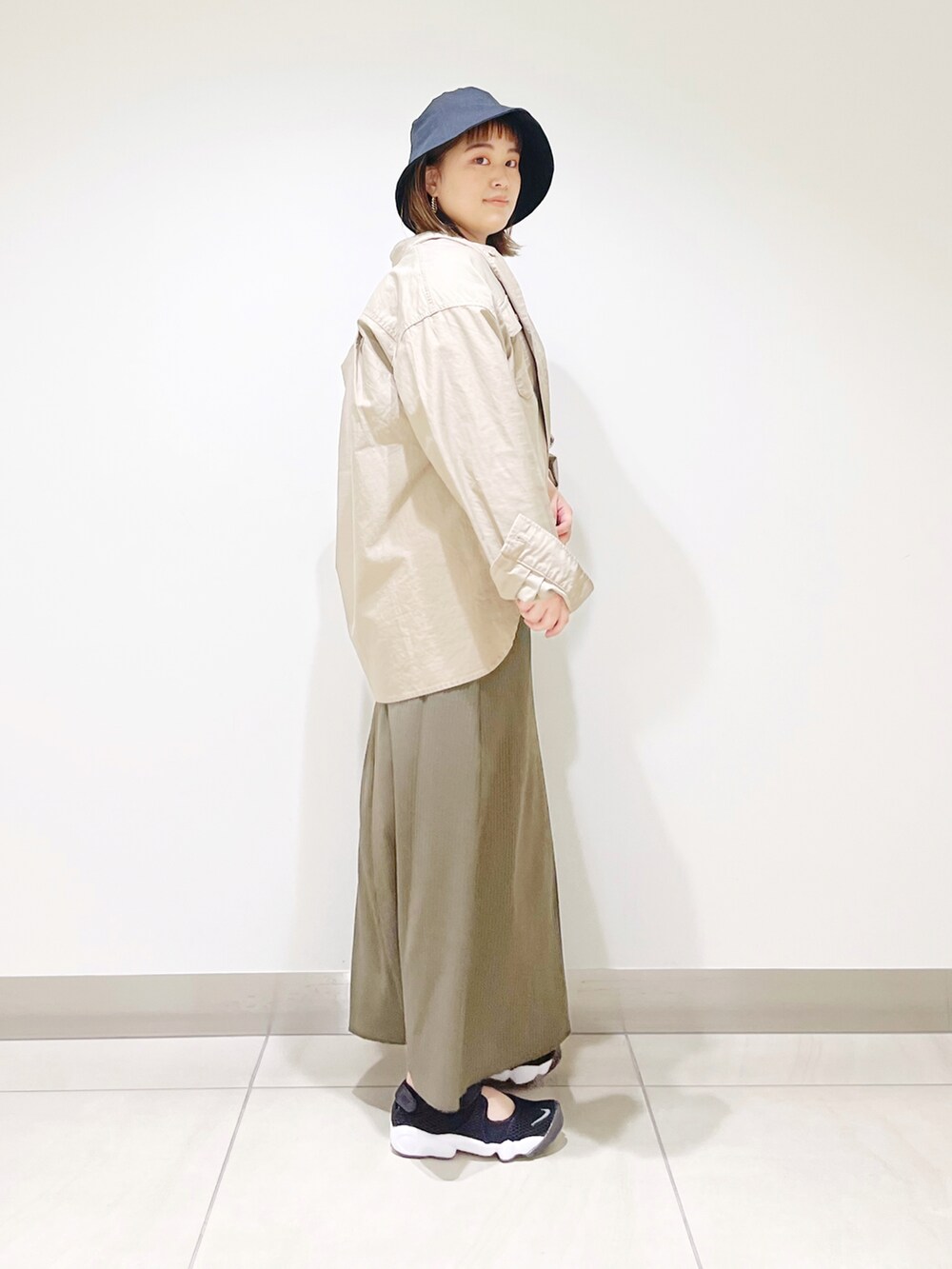 グリーン系のワンピース、ベージュ系のシャツ/ブラウス、ブラック系のスニーカーを着用したレディースの春コーディネートの5枚目の写真