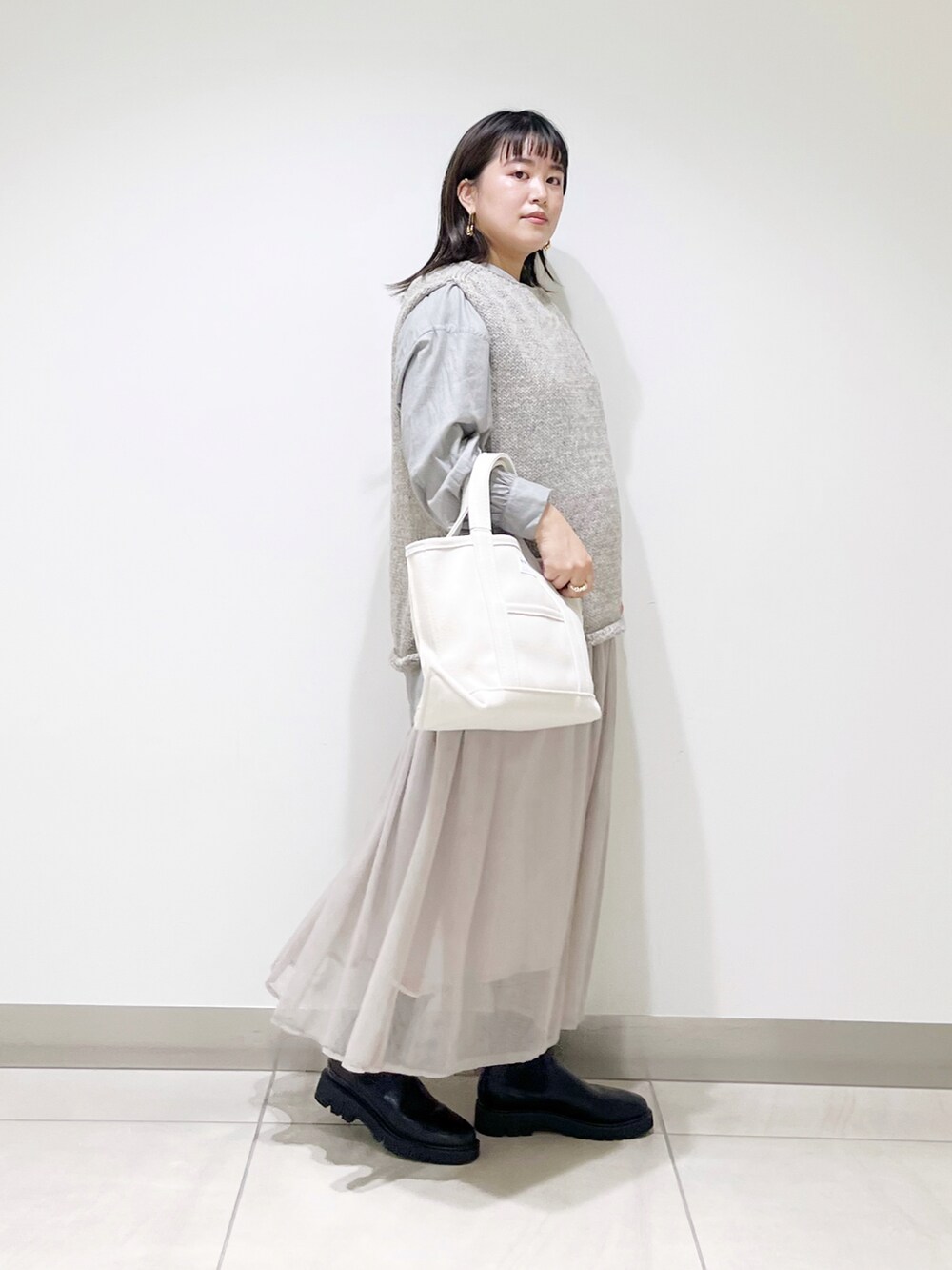グレー系のニット/セーター、ホワイト系のトートバッグ、グレー系のスカートを着用したレディースの秋コーディネートの4枚目の写真