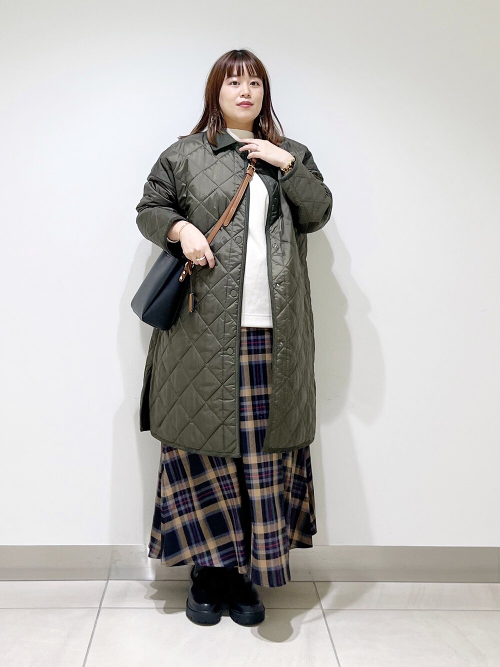 グリーン系のダウンジャケット/コート、ホワイト系のトップス、ブラウン系のスカートを着用したレディースの秋コーディネートの7枚目の写真