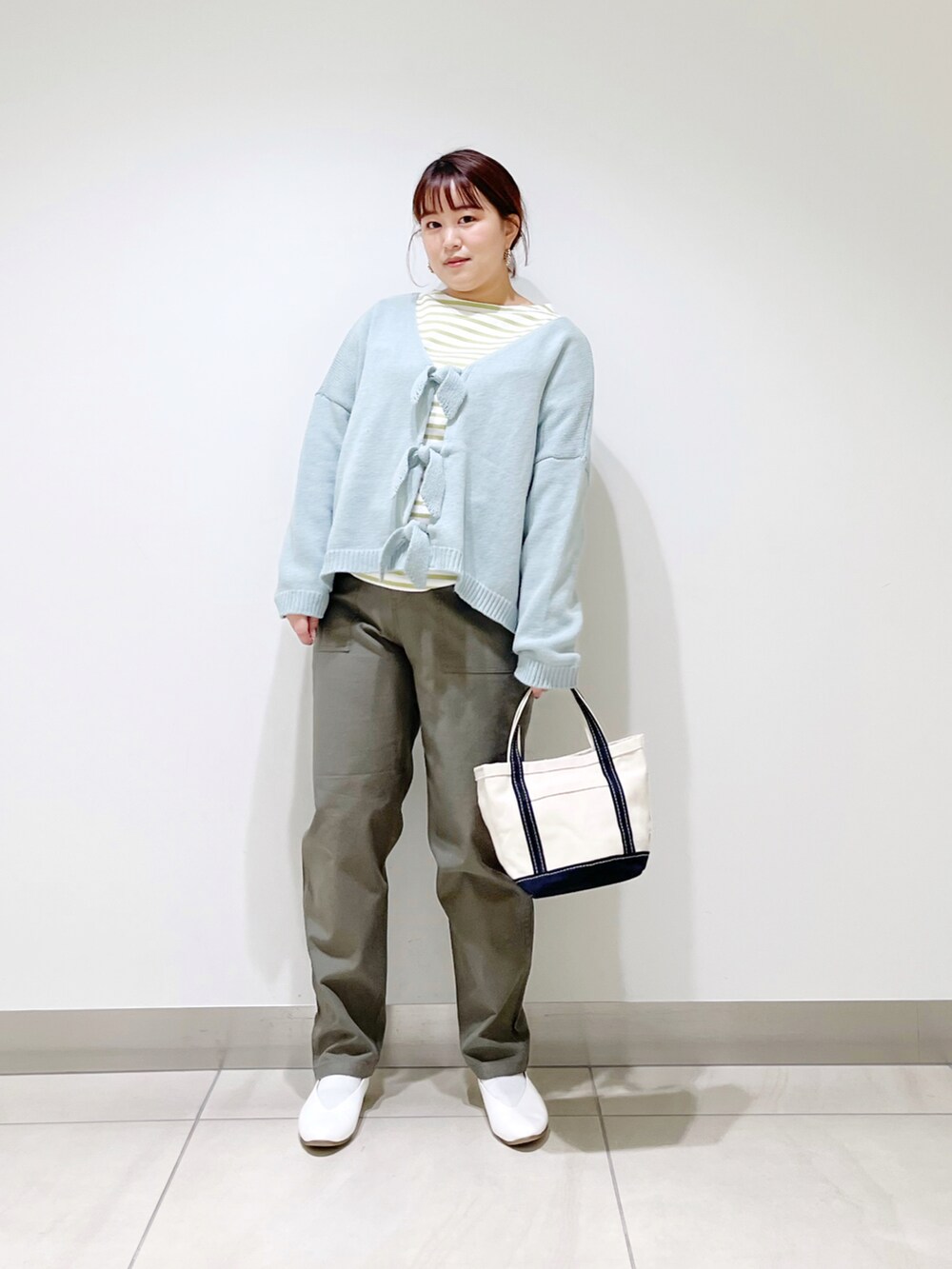 グリーン系のカーディガン/ボレロ、ブルー系のトートバッグ、ホワイト系のパンプスを着用したレディースの冬コーディネートの2枚目の写真