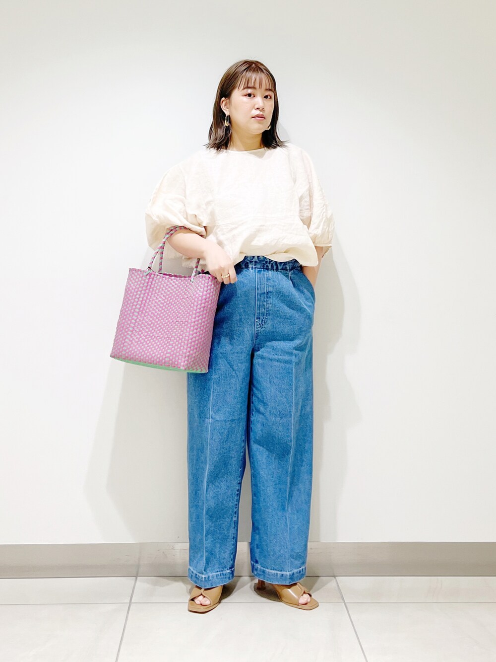 ベージュ系のシャツ/ブラウス、ピンク系のトートバッグ、ブルー系のデニムパンツを着用したレディースの春コーディネートの5枚目の写真