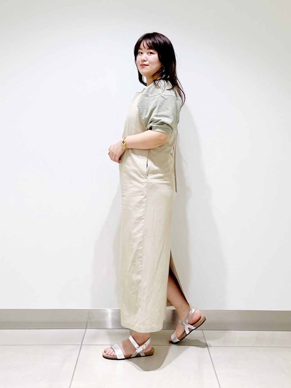 ベージュ系のワンピース、シルバー系のサンダル、グリーン系のTシャツ/カットソーを着用したレディースの春コーディネートの2枚目の写真
