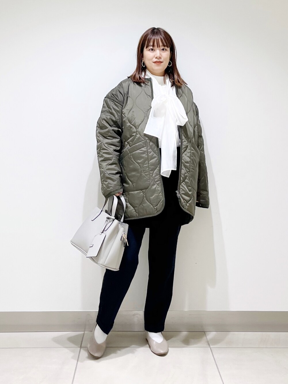 グリーン系のダウンジャケット/コート、ブルー系のパンツ、グレー系のトートバッグを着用したレディースの秋コーディネートの7枚目の写真