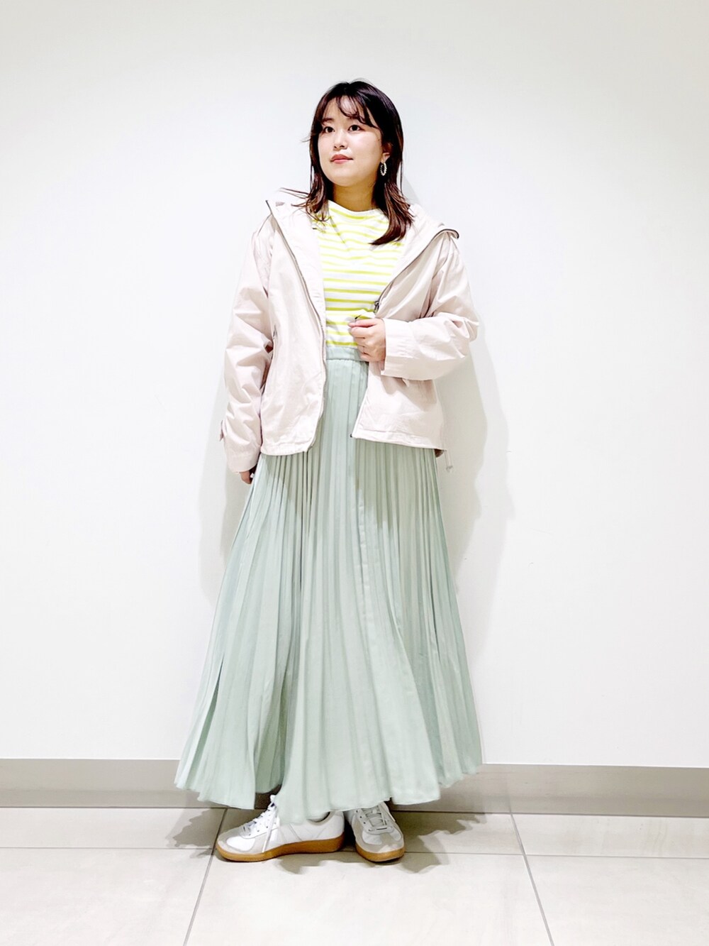 ベージュ系のブルゾン、イエロー系のTシャツ/カットソー、グリーン系のスカートを着用したレディースの春コーディネートの3枚目の写真