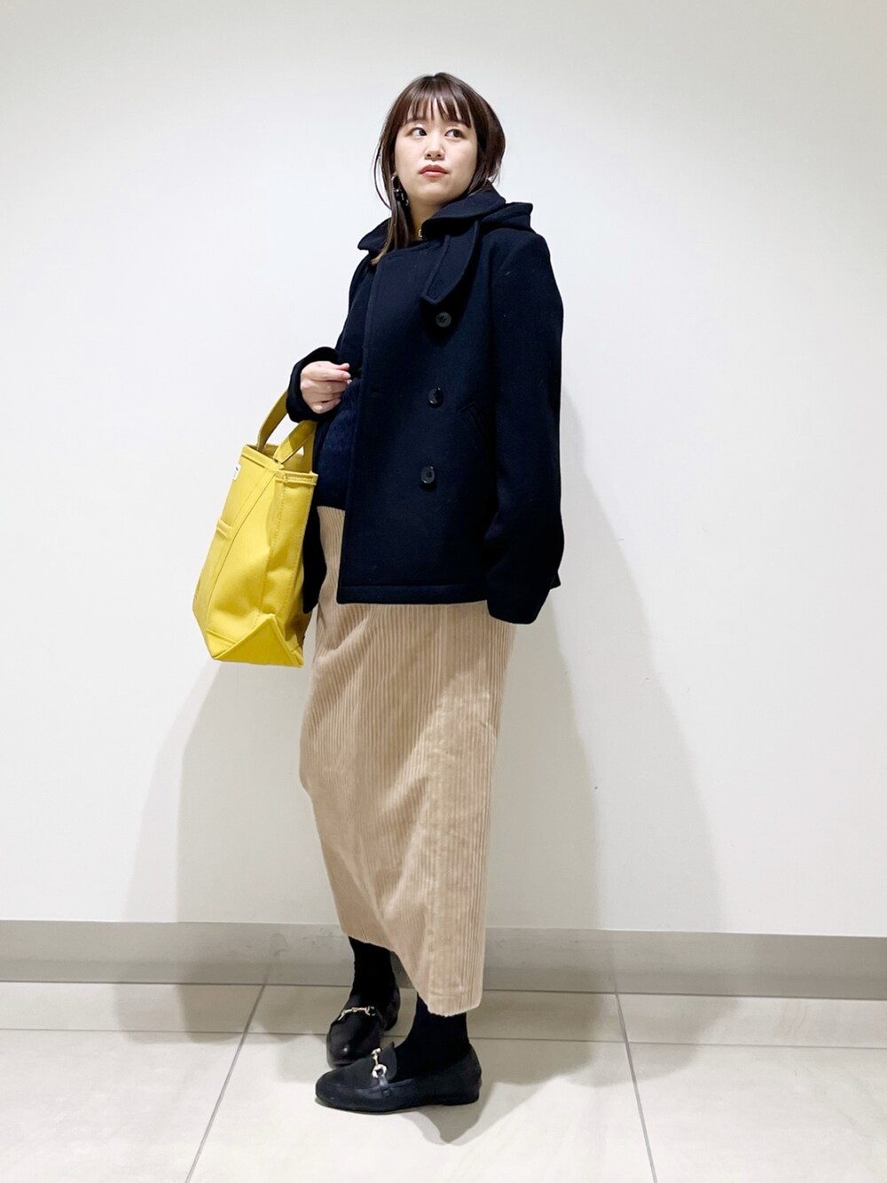 ブラック系のピーコート、ブルー系のニット/セーター、ブラック系のローファーを着用したレディースの冬コーディネートの5枚目の写真