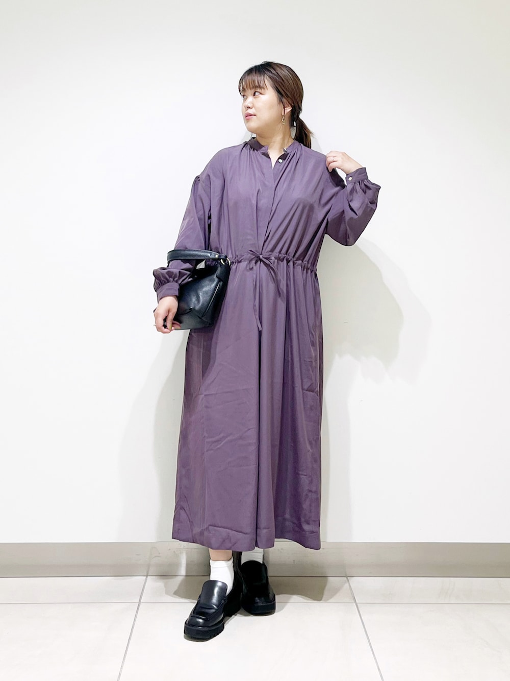 パープル系のワンピース、ブラック系のローファー、ブラック系のハンドバッグを着用したレディースの秋コーディネートの2枚目の写真