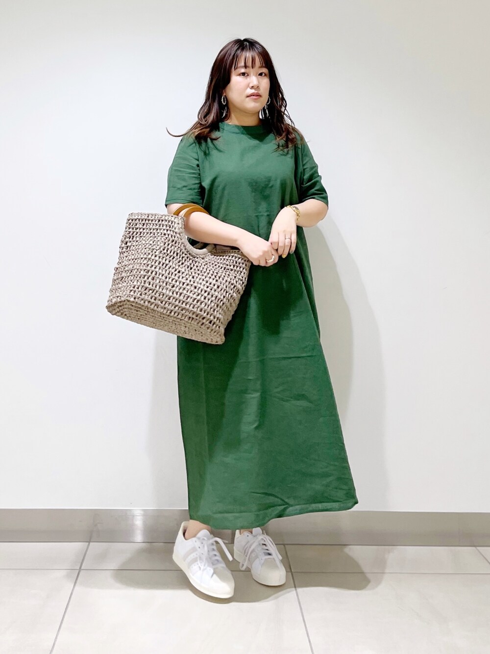 グリーン系のワンピース、グレー系のかごバッグ、ホワイト系のスニーカーを着用したレディースの夏コーディネートの5枚目の写真