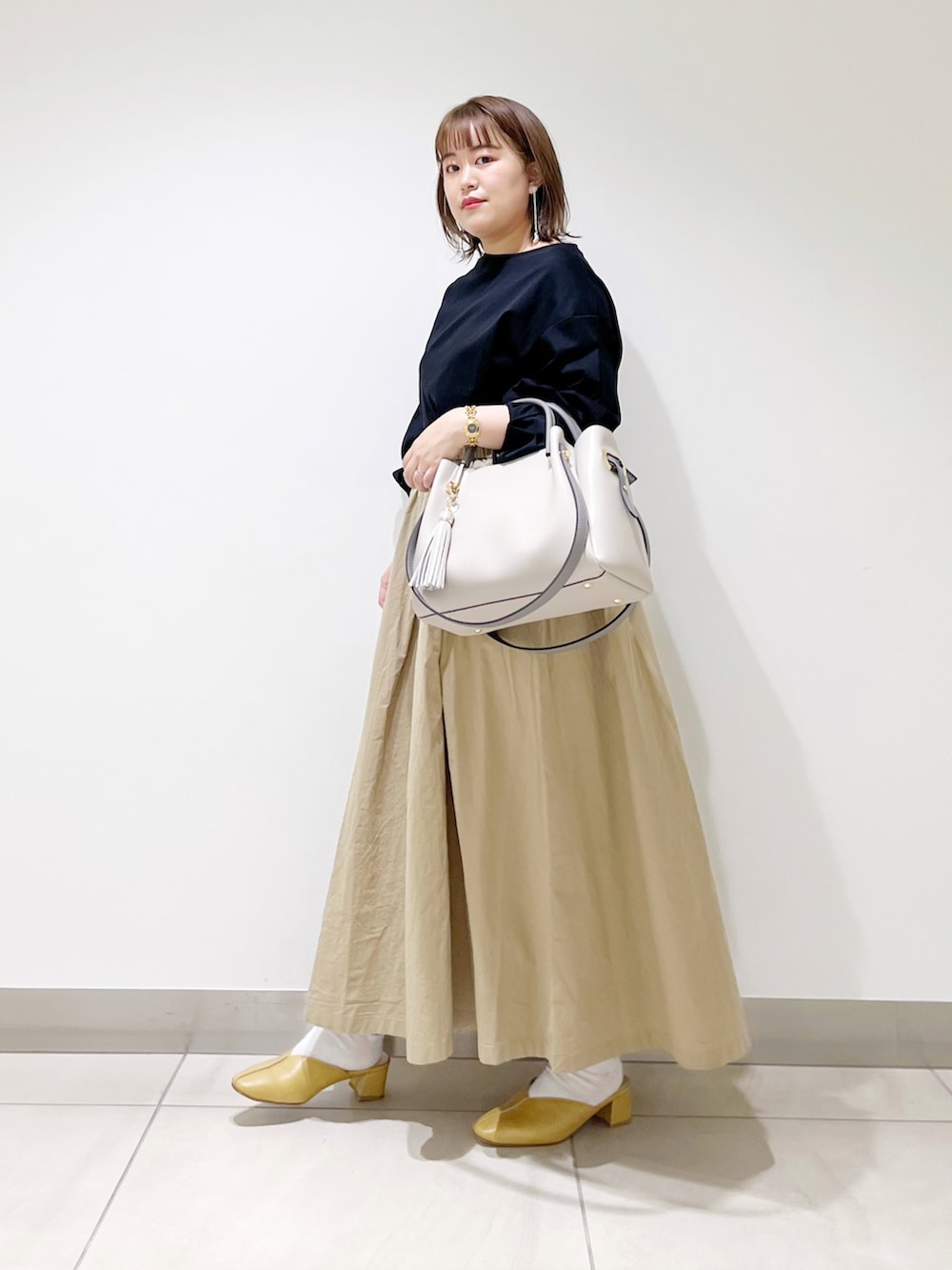 ブラック系のTシャツ/カットソー、ベージュ系のスカート、グレー系のトートバッグを着用したレディースの春コーディネートの4枚目の写真