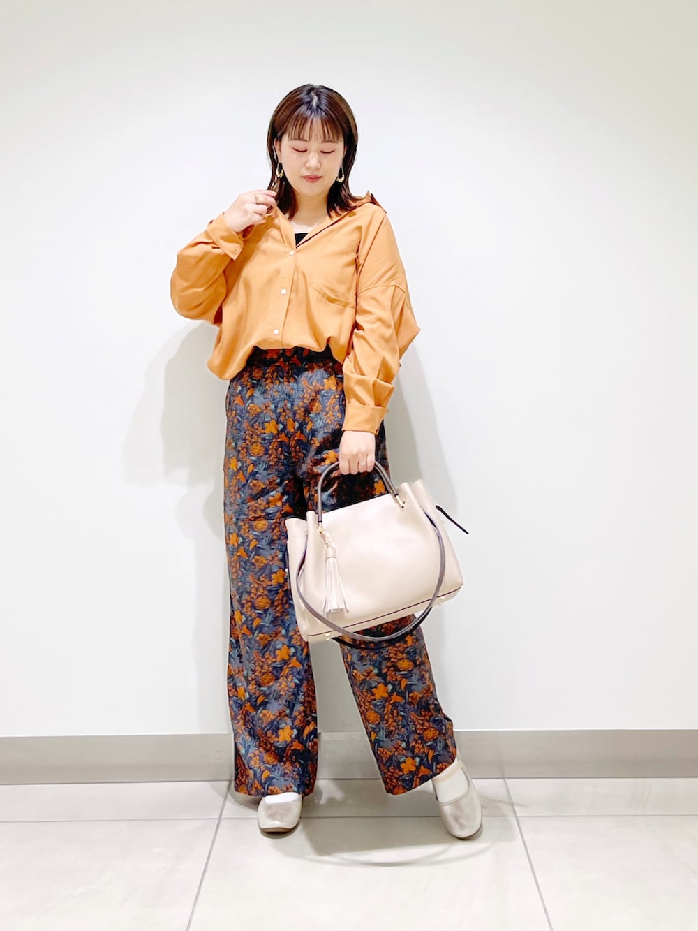 オレンジ系のシャツ/ブラウス、ベージュ系のトートバッグ、ゴールド系のその他シューズを着用したレディースの夏コーディネートの2枚目の写真