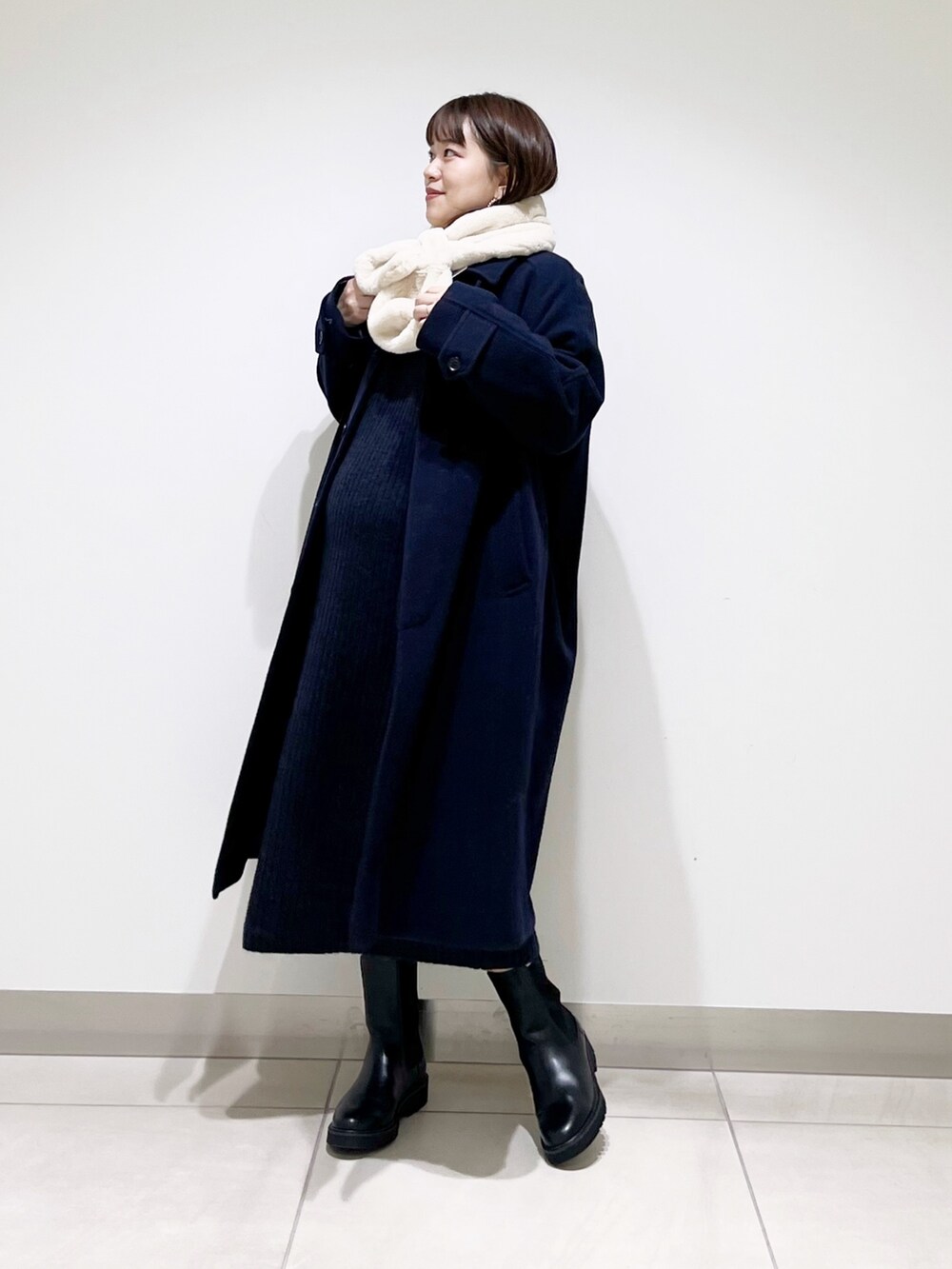 ブルー系のステンカラーコート、ブルー系のワンピース、ブラック系のブーツを着用したレディースの冬コーディネートの2枚目の写真