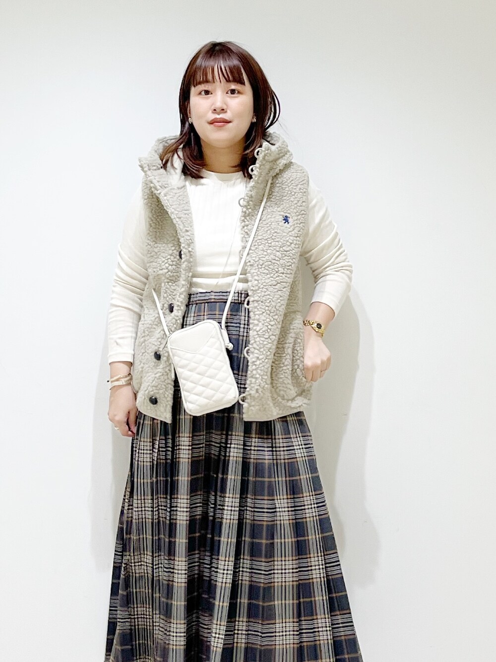 ホワイト系のトップス、グレー系のスカート、ブラック系のブーツを着用したレディースの秋コーディネートの4枚目の写真