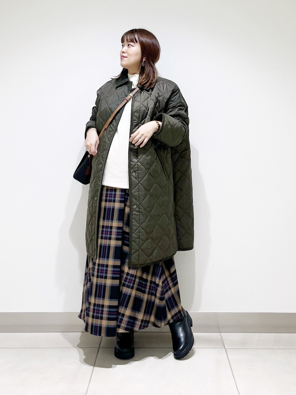 グリーン系のダウンジャケット/コート、ホワイト系のトップス、ブラウン系のスカートを着用したレディースの秋コーディネートの6枚目の写真