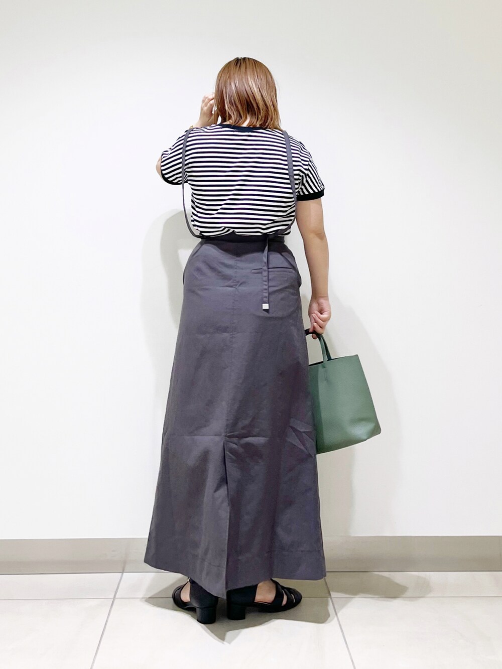 グレー系のワンピース、グリーン系のトートバッグ、ブラック系のサンダルを着用したレディースの春コーディネートの4枚目の写真