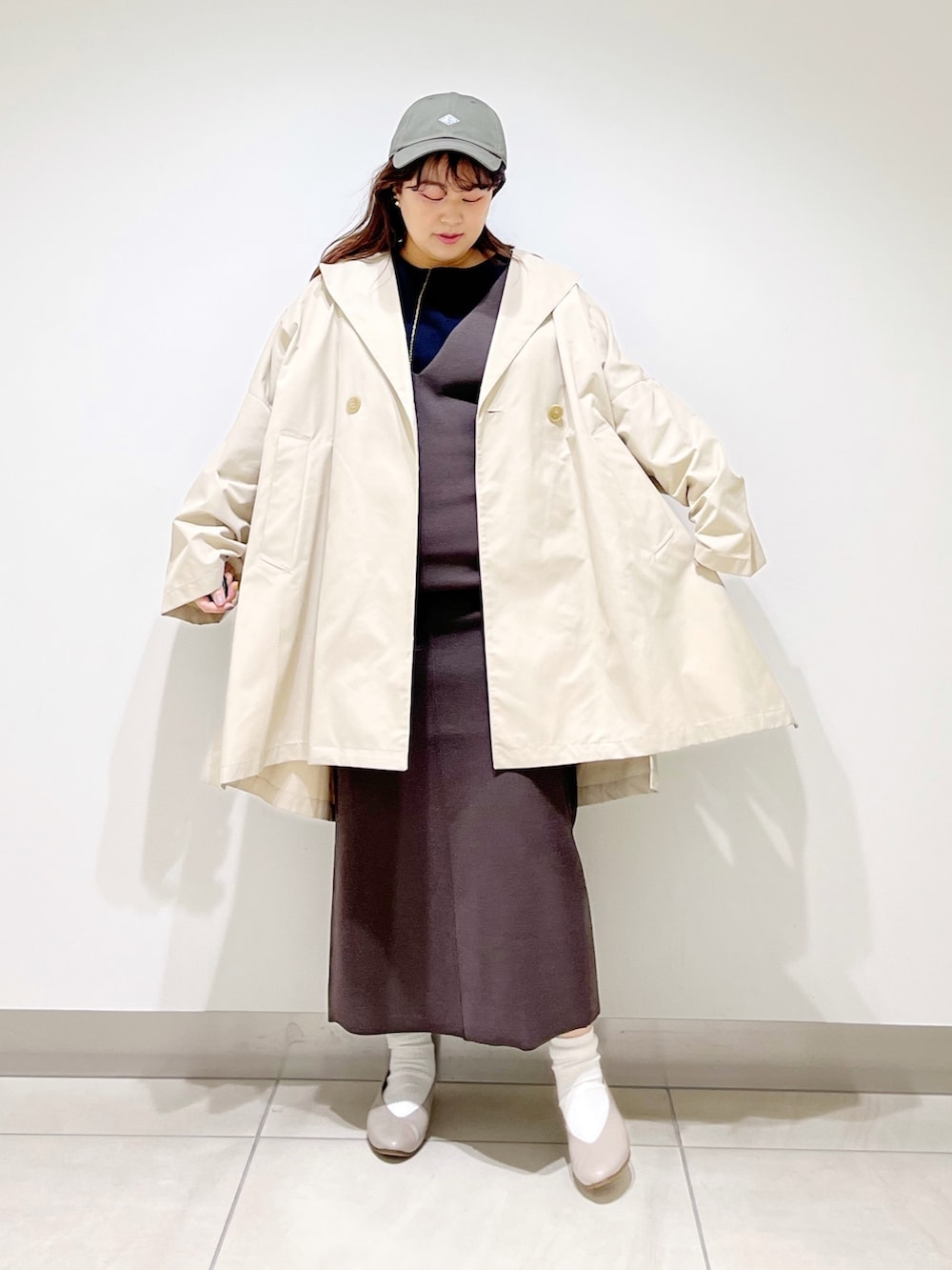 ベージュ系のポンチョ、ブラウン系のワンピース、ベージュ系のパンプスを着用したレディースの春コーディネートの2枚目の写真
